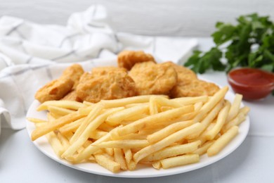 Photo of Tasty chicken nuggets and french fries with sauce on white tiled table, closeup
