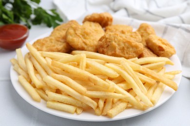 Photo of Tasty chicken nuggets and french fries with sauce on white tiled table, closeup