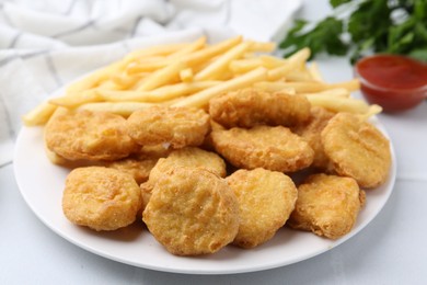 Photo of Tasty chicken nuggets and french fries with sauce on white tiled table, closeup