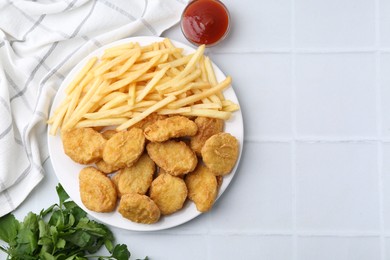 Photo of Tasty chicken nuggets and french fries with sauce on white tiled table, flat lay. Space for text