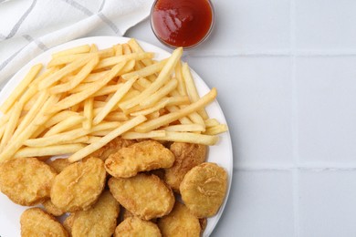 Photo of Tasty chicken nuggets and french fries with sauce on white tiled table, flat lay. Space for text
