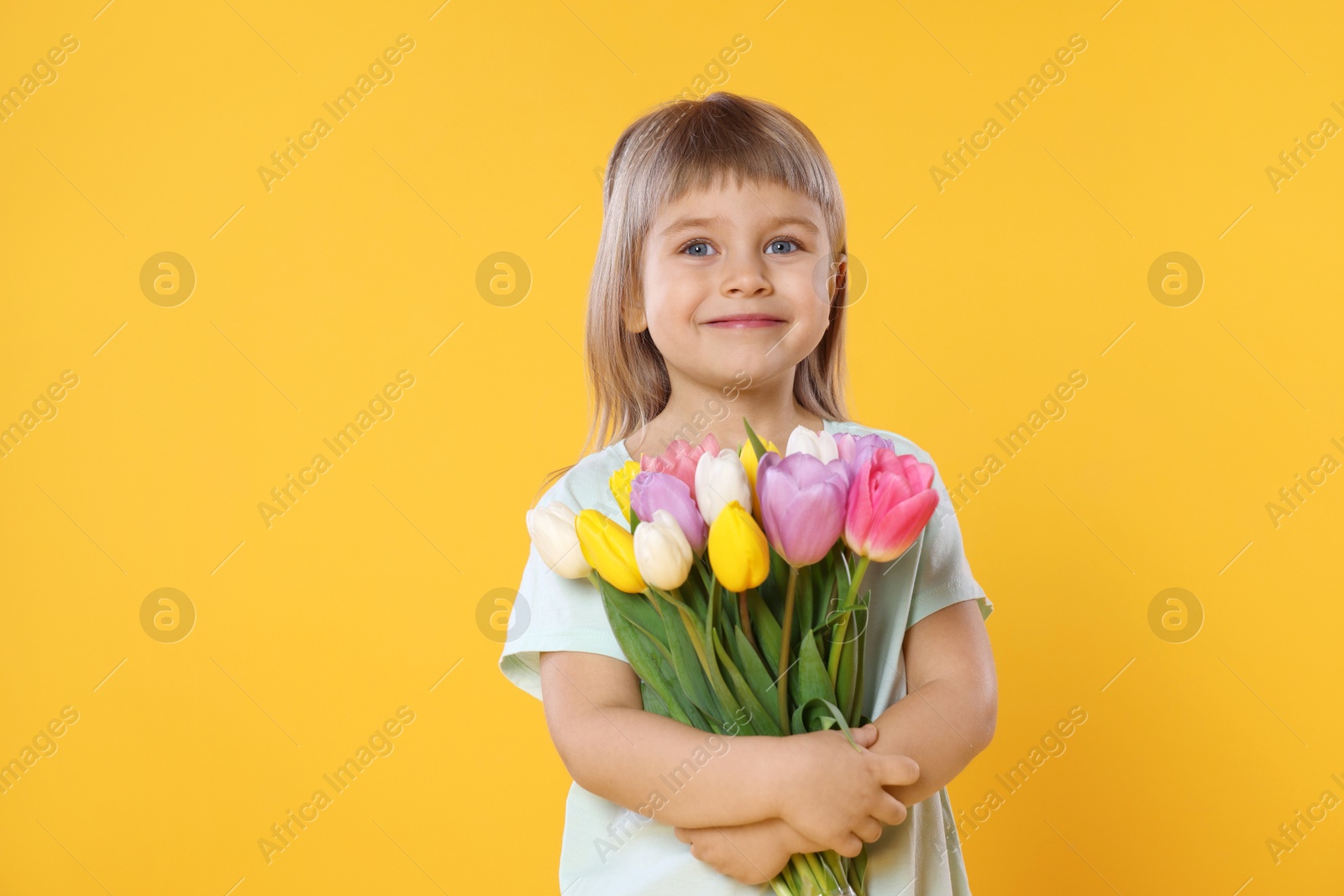 Photo of Cute little girl with bouquet of tulips on yellow background. Space for text