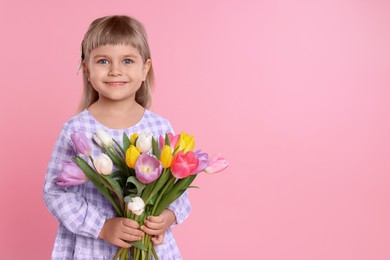 Photo of Smiling little girl with bouquet of tulips on pink background. Space for text