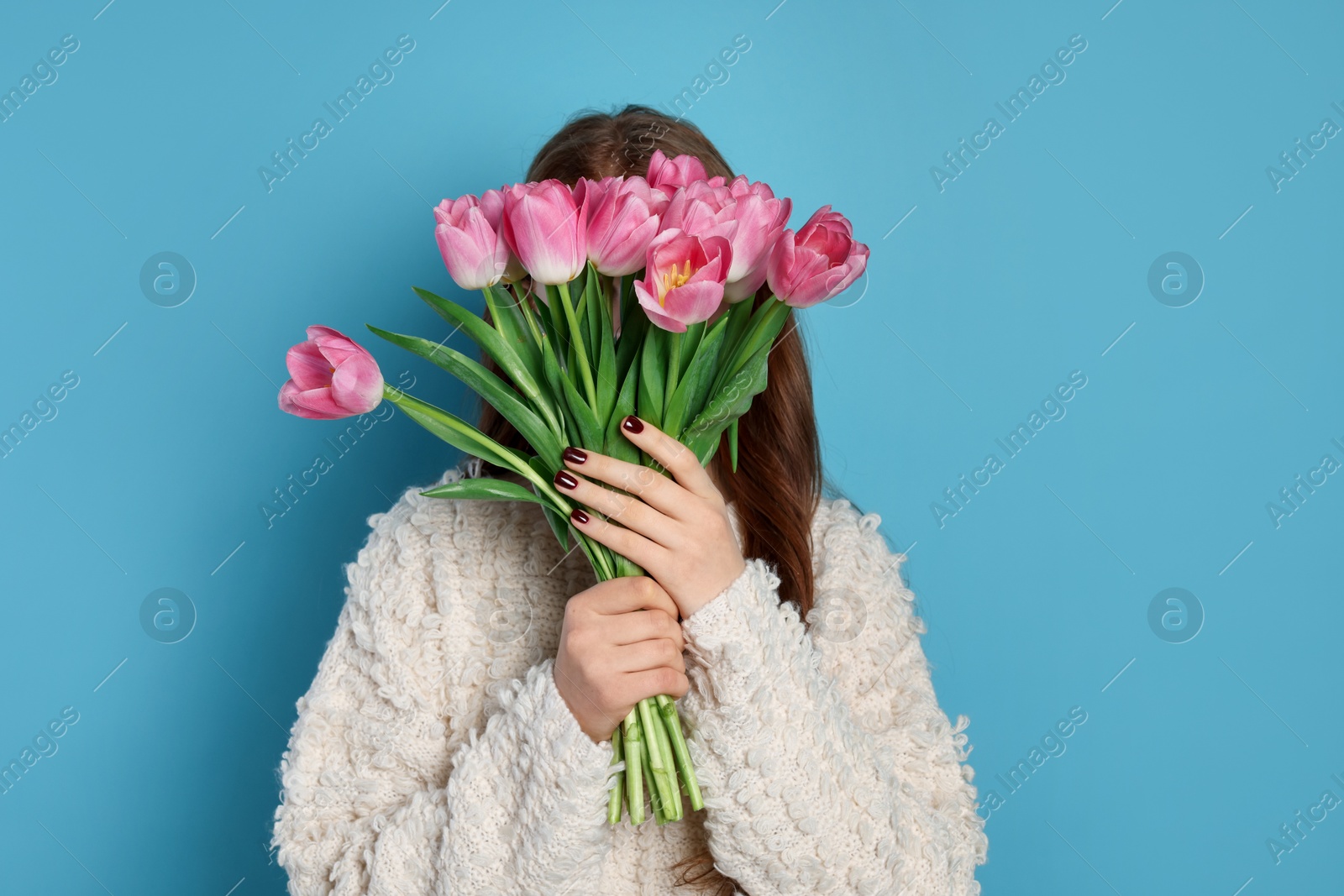 Photo of Teenage girl with bouquet of tulips on light blue background