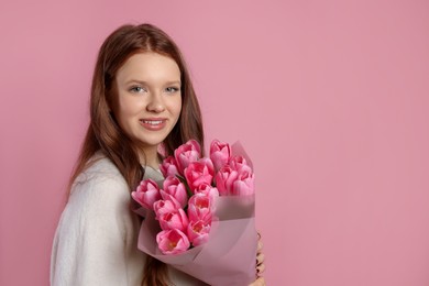 Photo of Beautiful teenage girl with bouquet of tulips on pink background, space for text