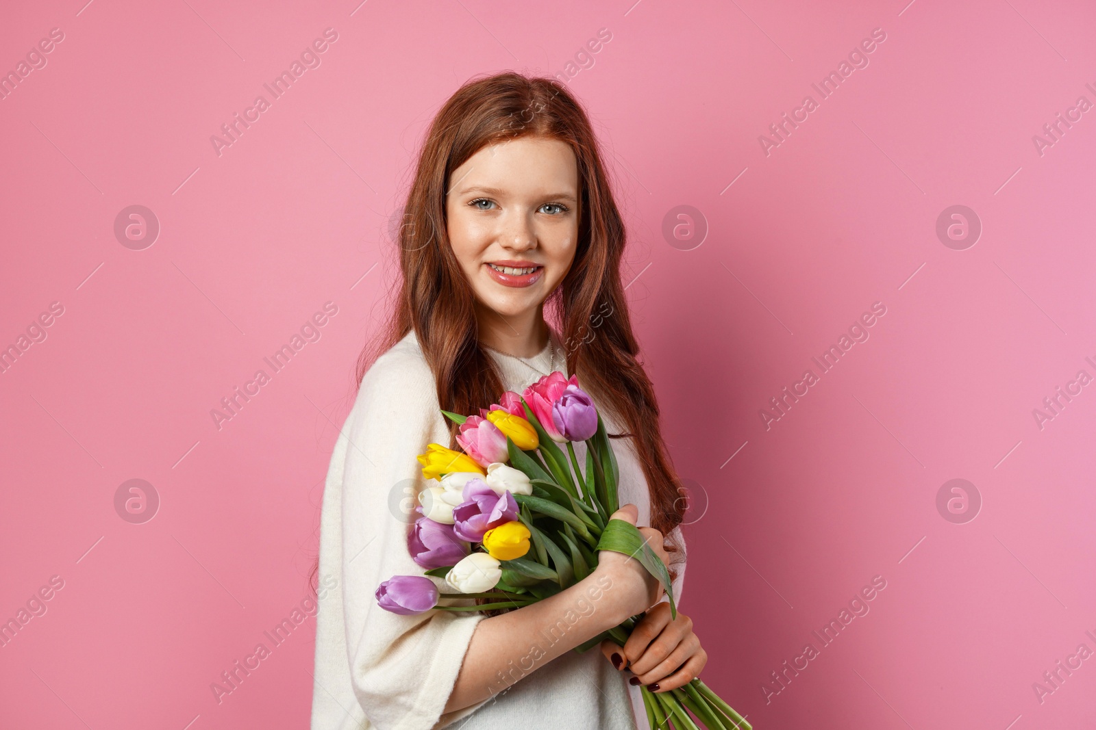 Photo of Beautiful teenage girl with bouquet of tulips on pink background