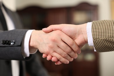 Photo of Notary shaking hands with client in office, closeup