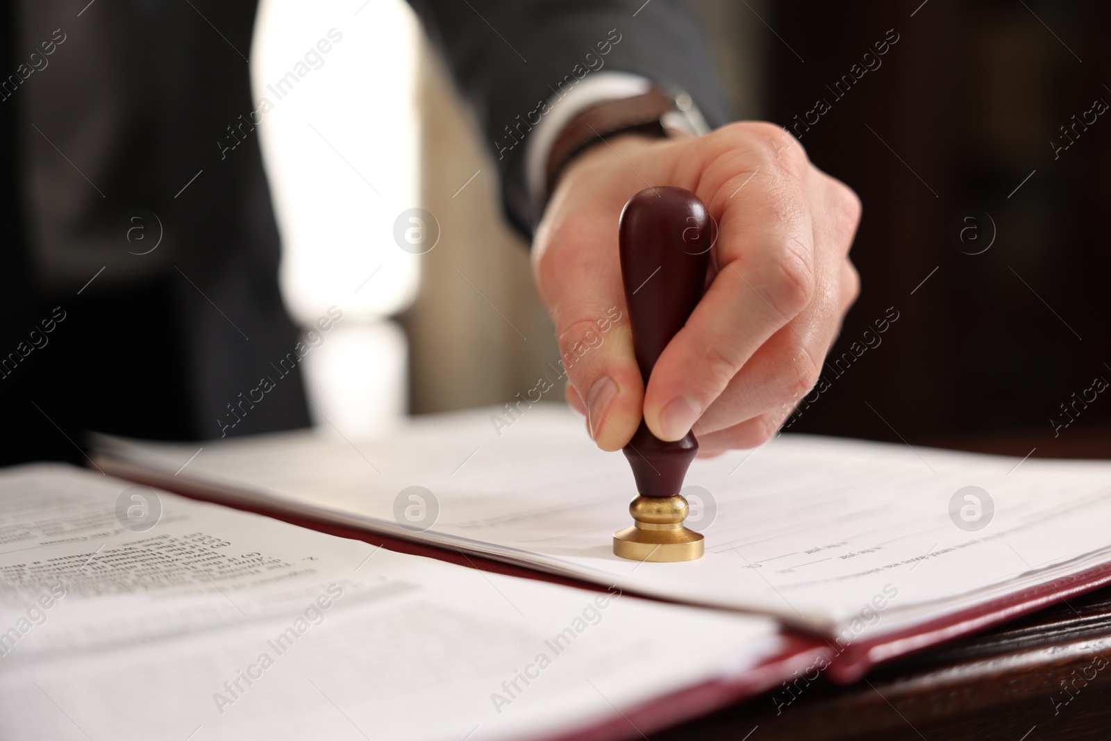 Photo of Notary stamping document at table in office, closeup