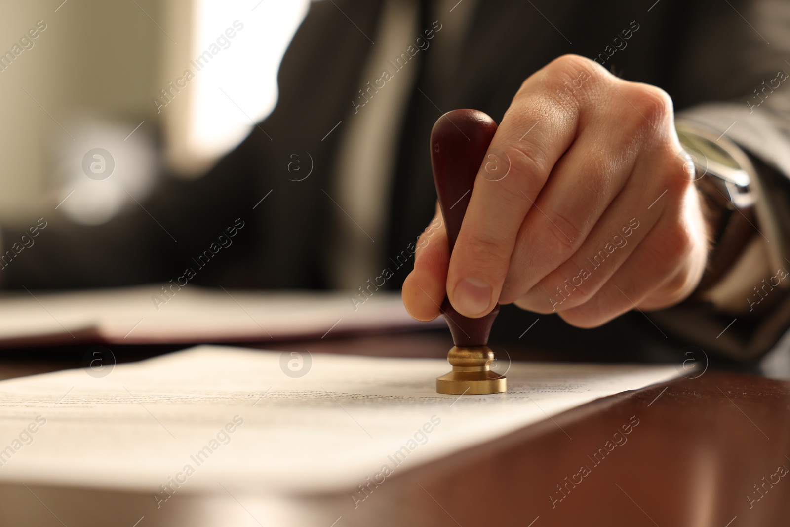 Photo of Notary stamping document at table in office, closeup