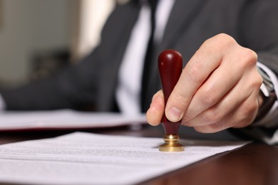 Photo of Notary stamping document at table in office, closeup