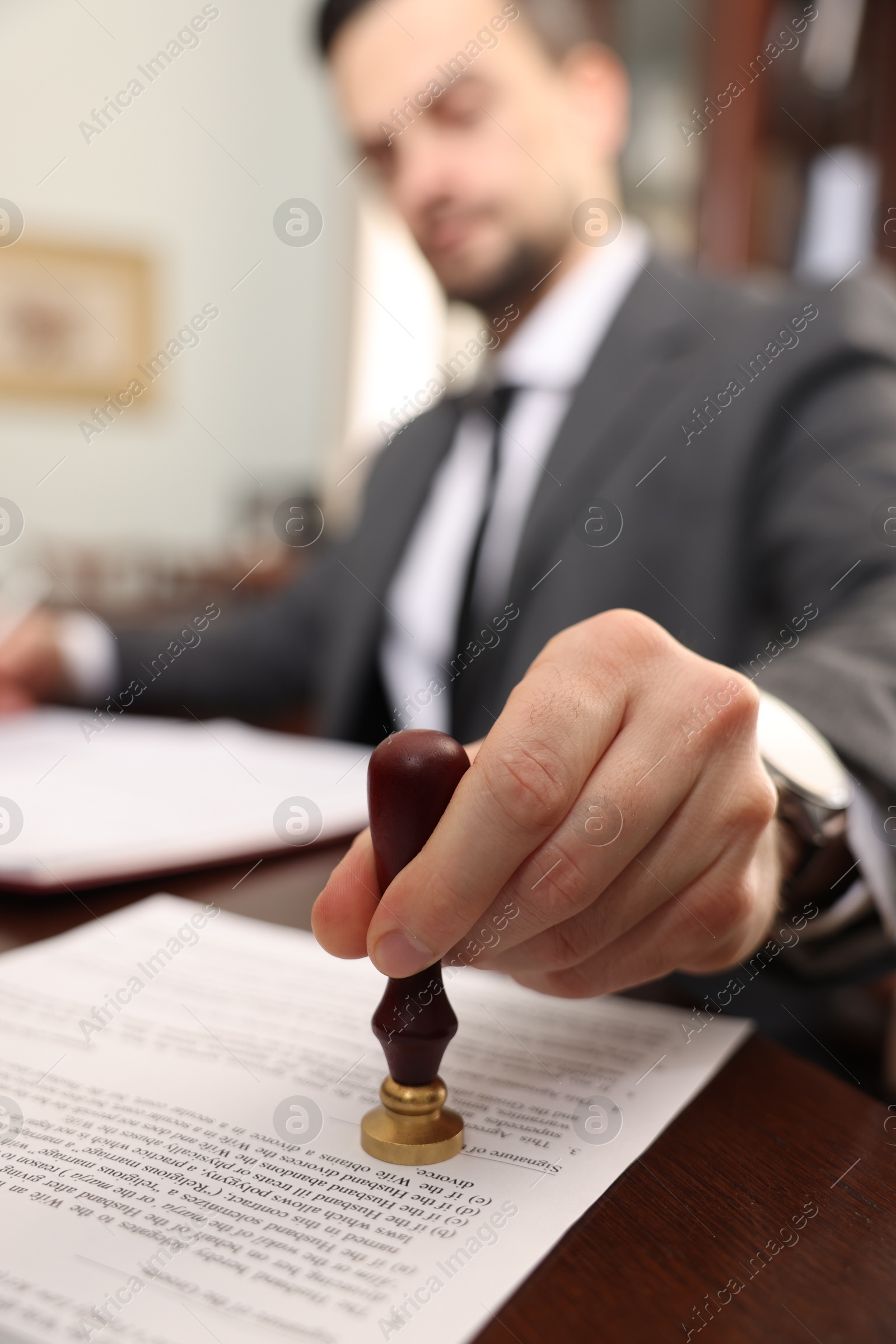 Photo of Notary stamping document at table in office, selective focus