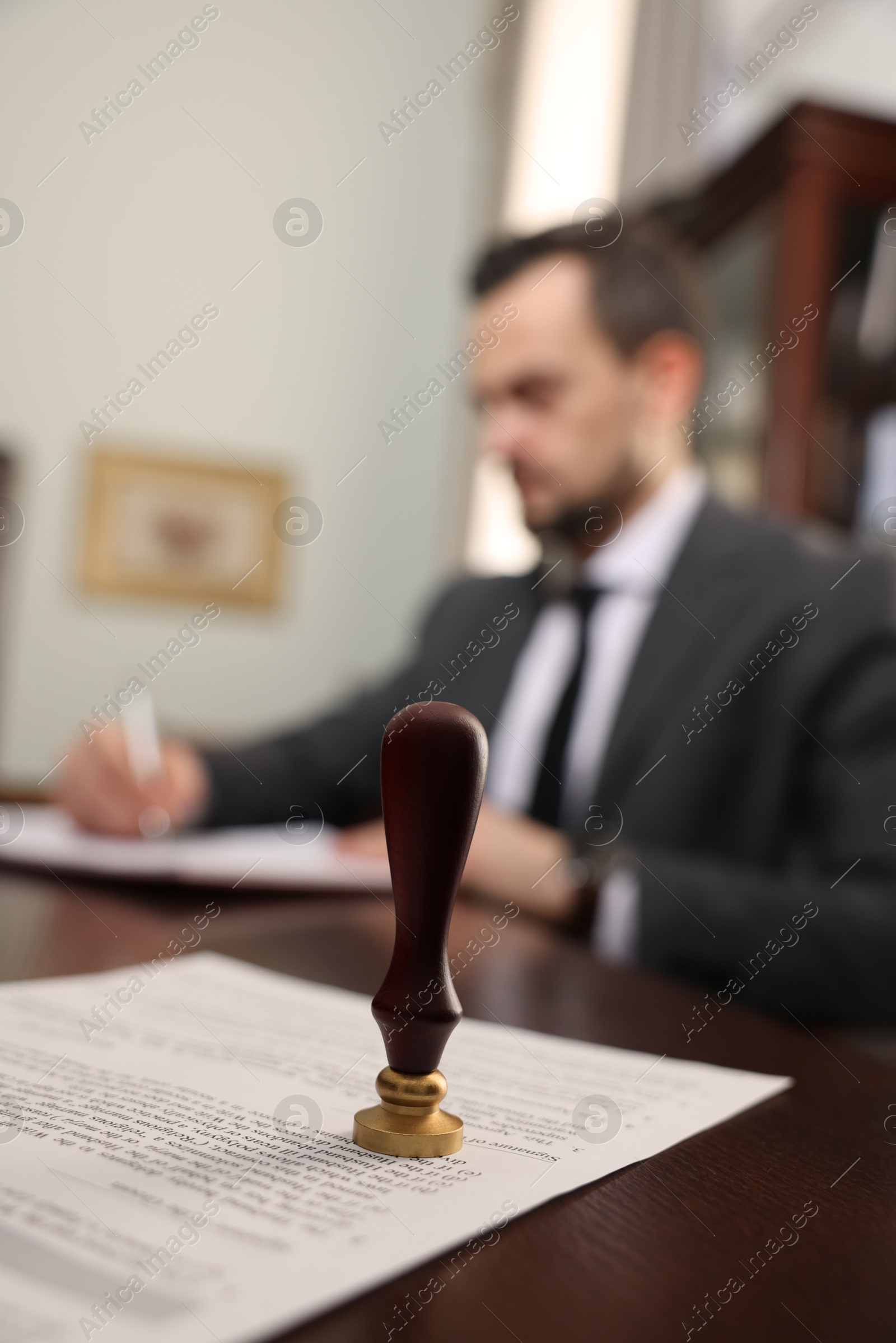 Photo of Notary working at table in office, focus on stamp