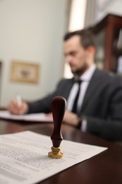 Photo of Notary working at table in office, focus on stamp