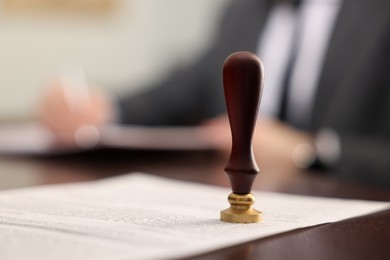 Photo of Notary working at table in office, focus on stamp