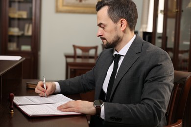 Photo of Notary signing document at table in office