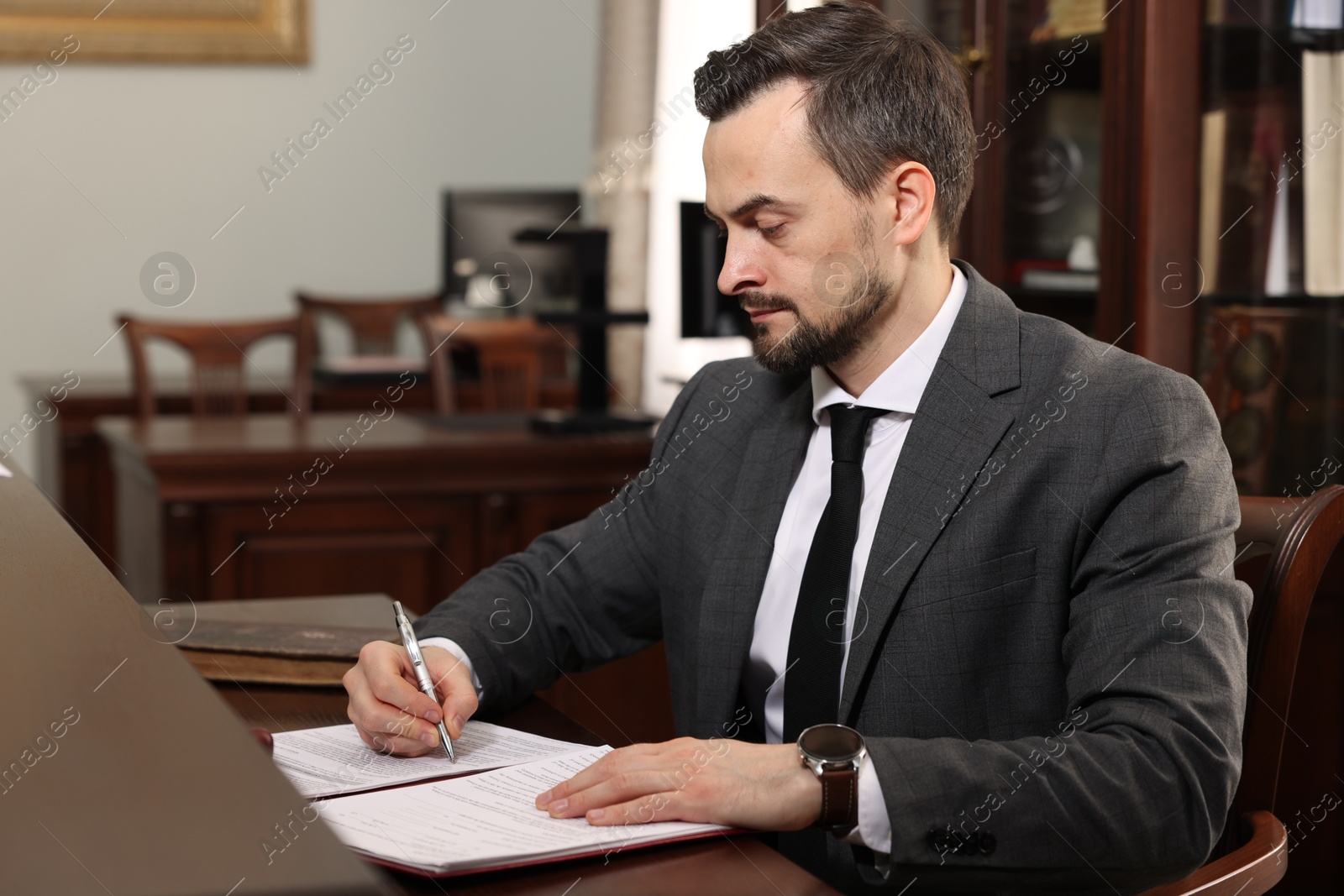 Photo of Notary signing document at table in office