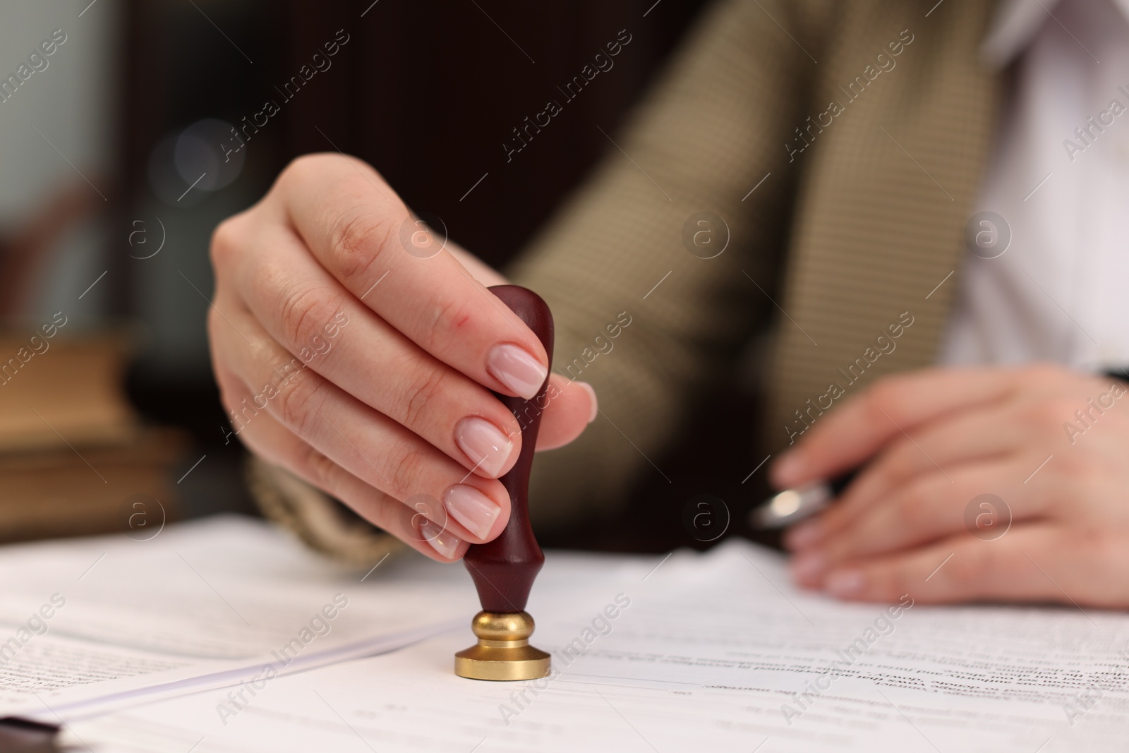 Photo of Notary stamping document at table in office, closeup