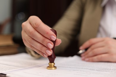 Notary stamping document at table in office, closeup