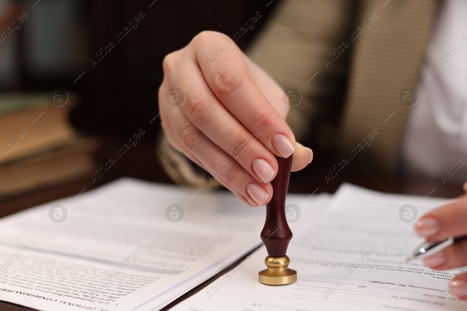 Photo of Notary stamping document at table in office, closeup