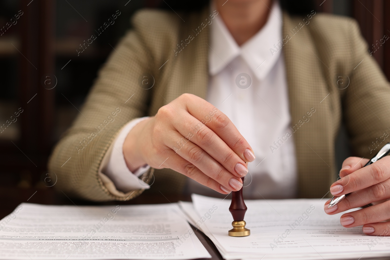 Photo of Notary stamping document at table in office, closeup