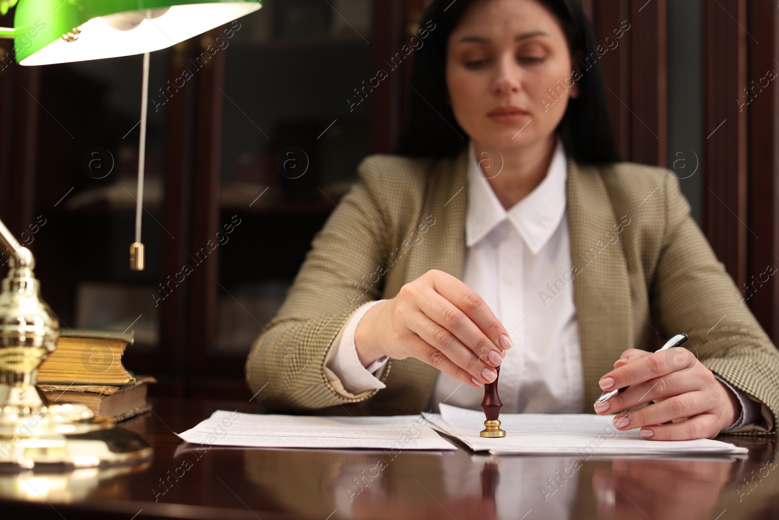 Photo of Notary stamping document at table in office