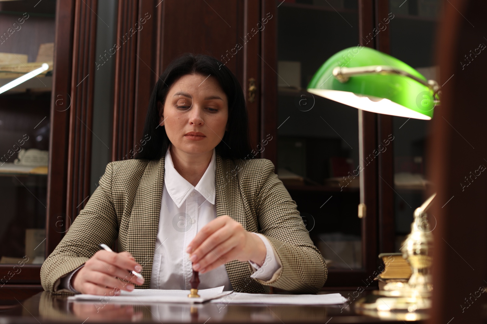 Photo of Notary stamping document at table in office