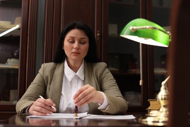 Photo of Notary stamping document at table in office