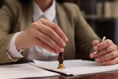 Photo of Notary stamping document at table in office, closeup