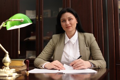 Photo of Notary signing document at table in office