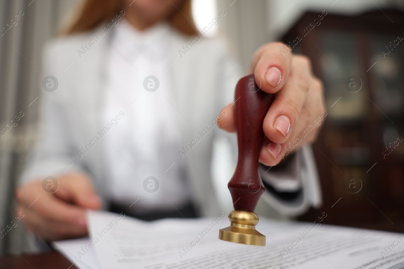 Photo of Notary stamping document at table in office, selective focus