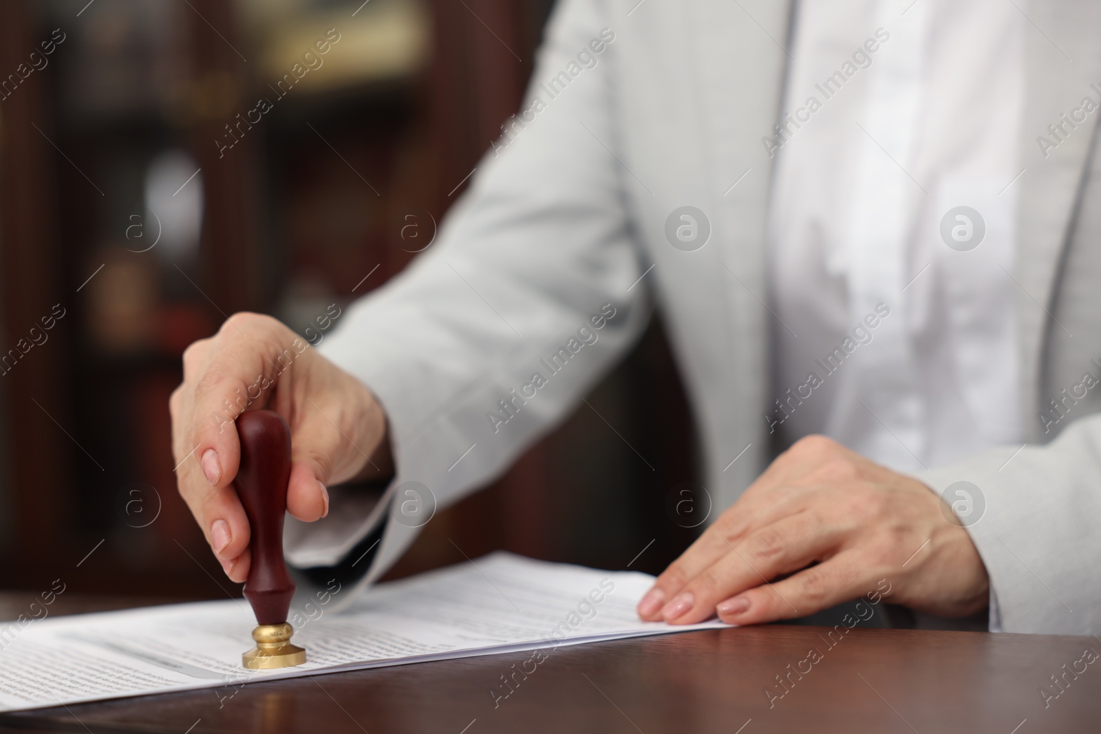 Photo of Notary stamping document at table in office, closeup