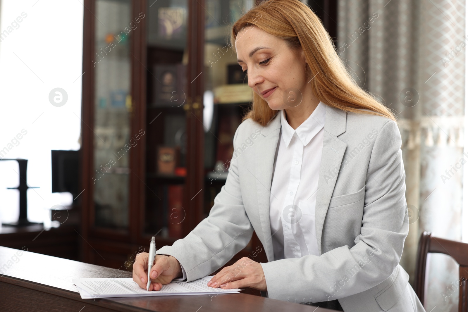 Photo of Notary signing document at counter in office