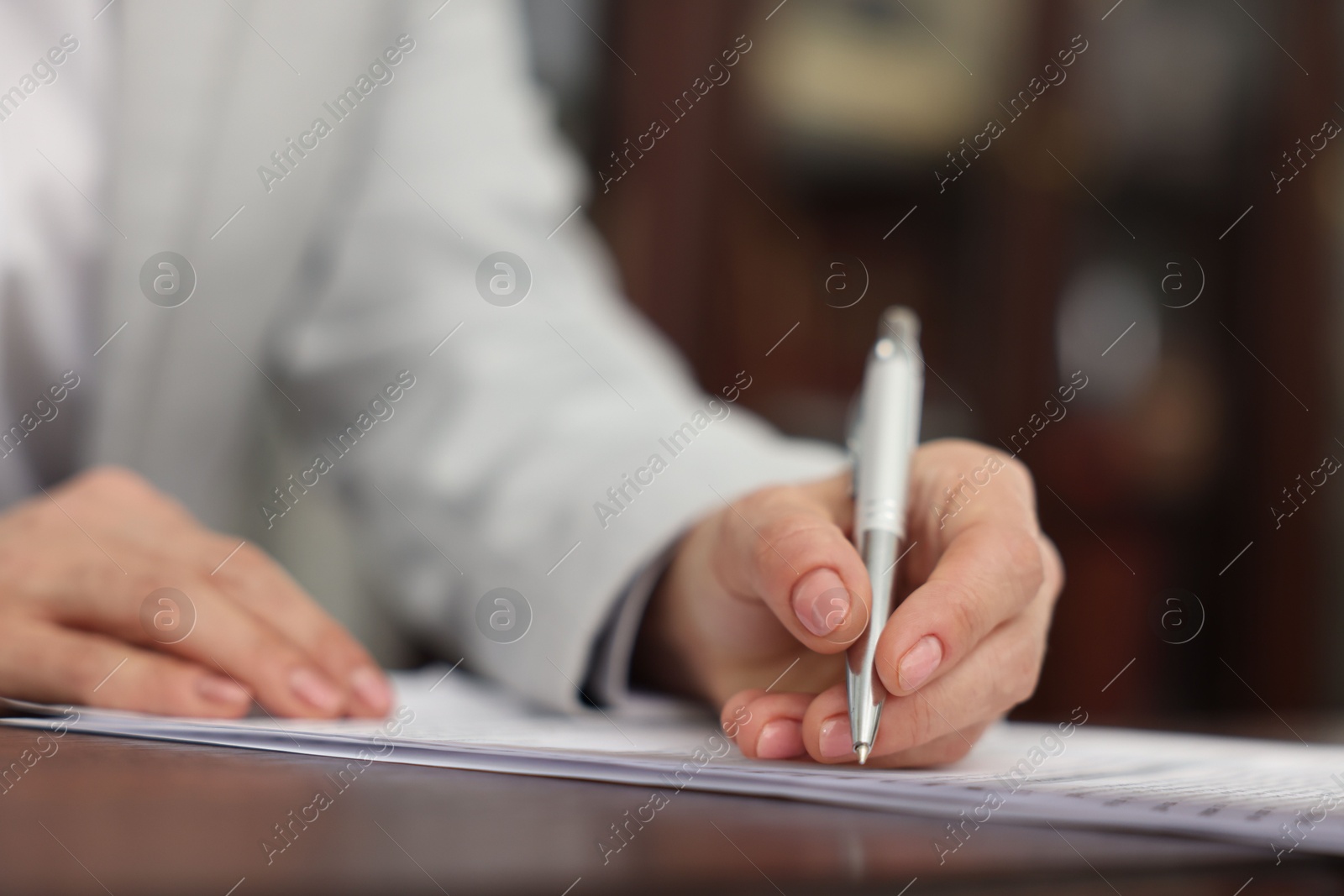 Photo of Notary signing document at table in office, closeup