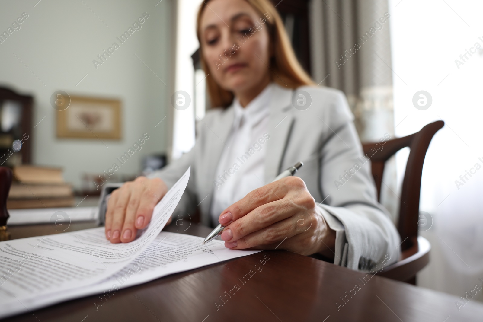 Photo of Notary signing document at table in office, selective focus