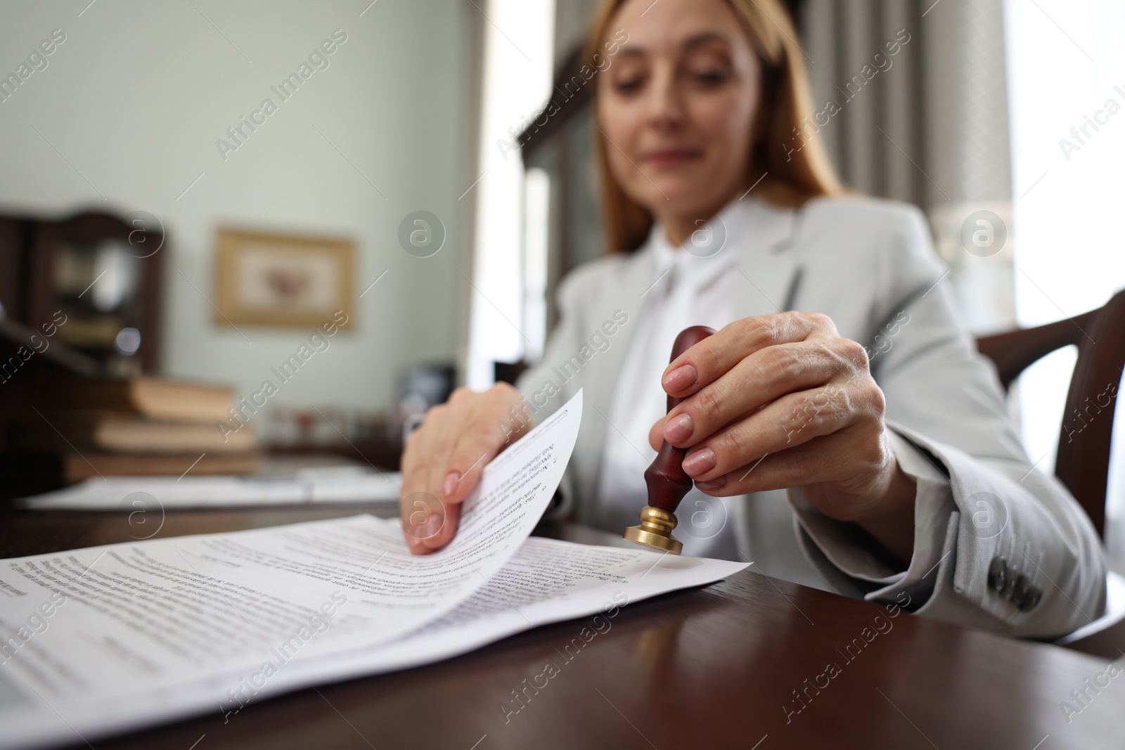 Photo of Notary stamping document at table in office, selective focus