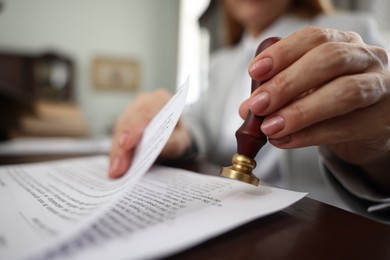 Photo of Notary stamping document at table in office, selective focus