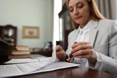 Photo of Notary stamping document at table in office, selective focus