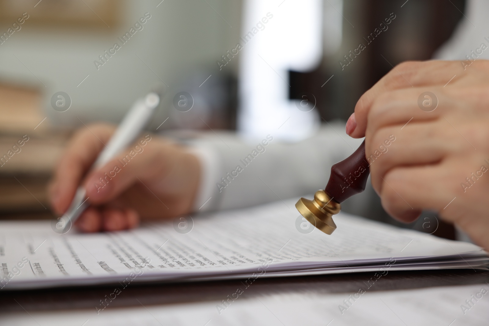 Photo of Notary stamping document at table in office, selective focus