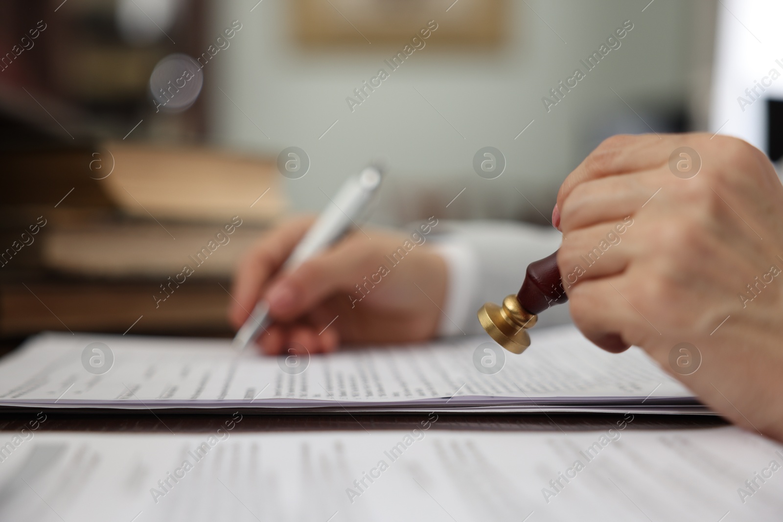 Photo of Notary stamping document at table in office, selective focus