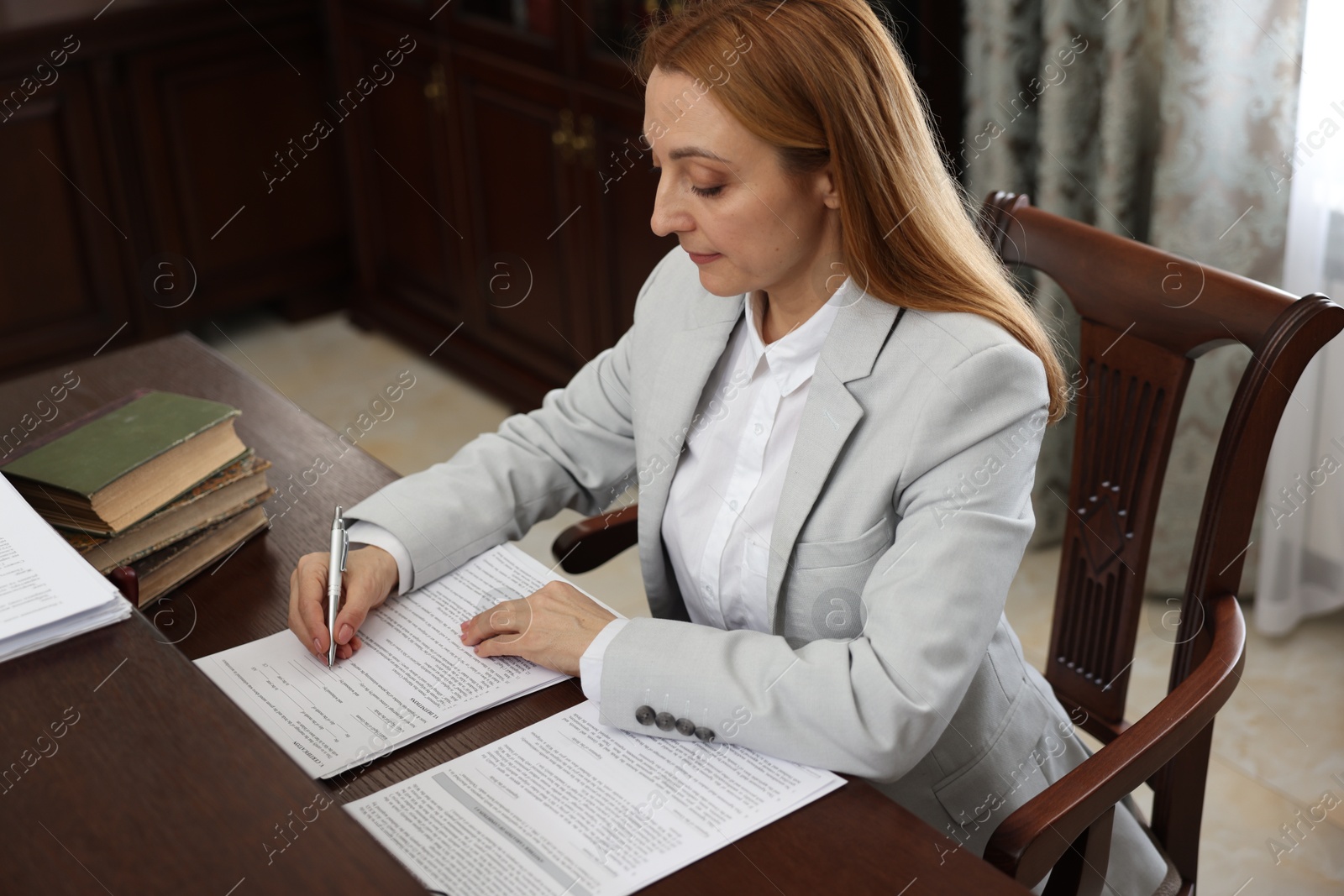 Photo of Notary signing document at table in office