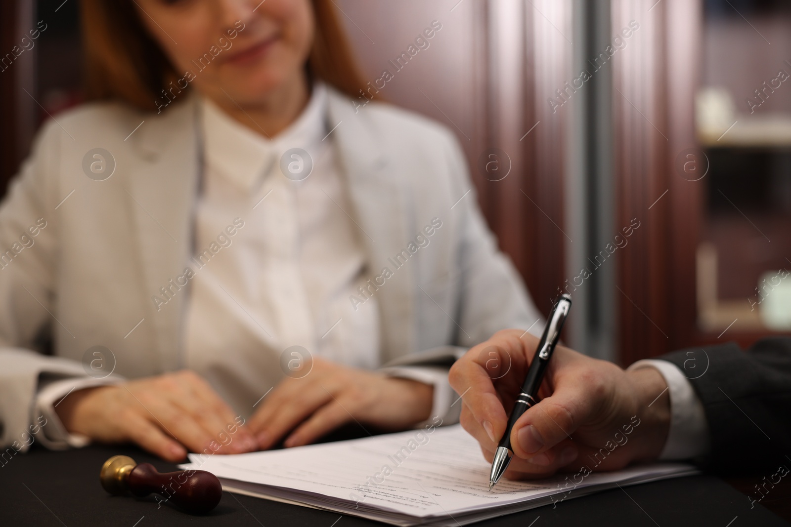 Photo of Notary working with client at table in office, selective focus