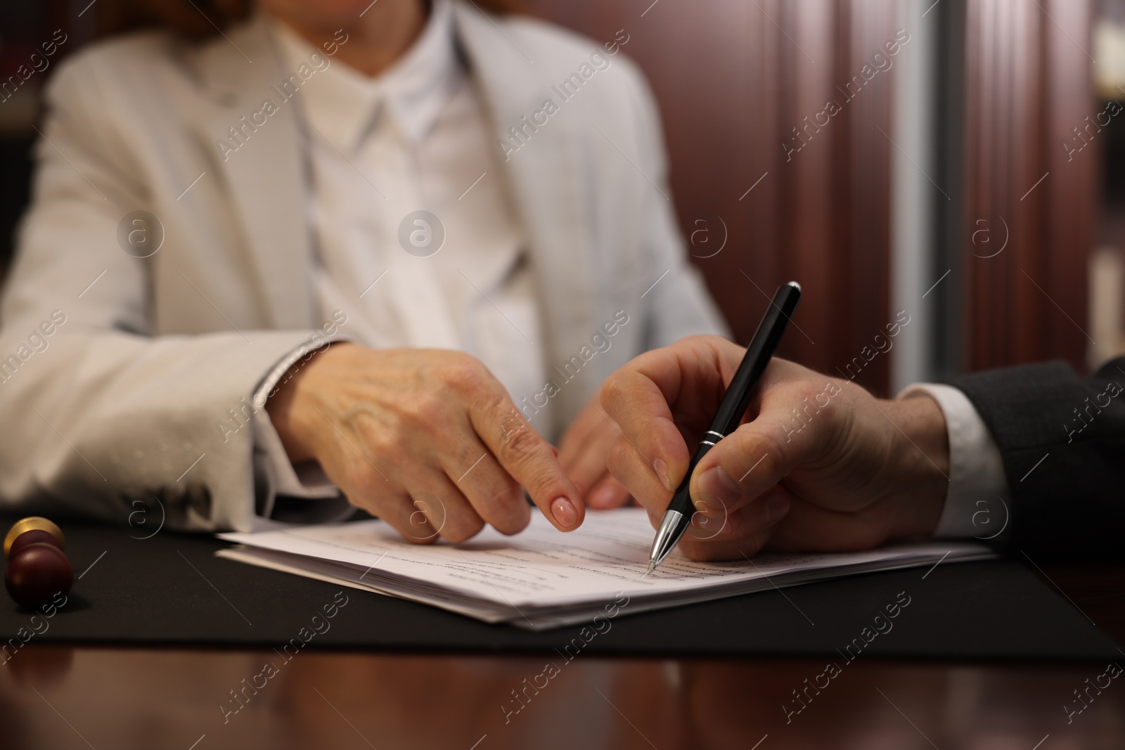 Photo of Notary showing client where to sign document in office, closeup