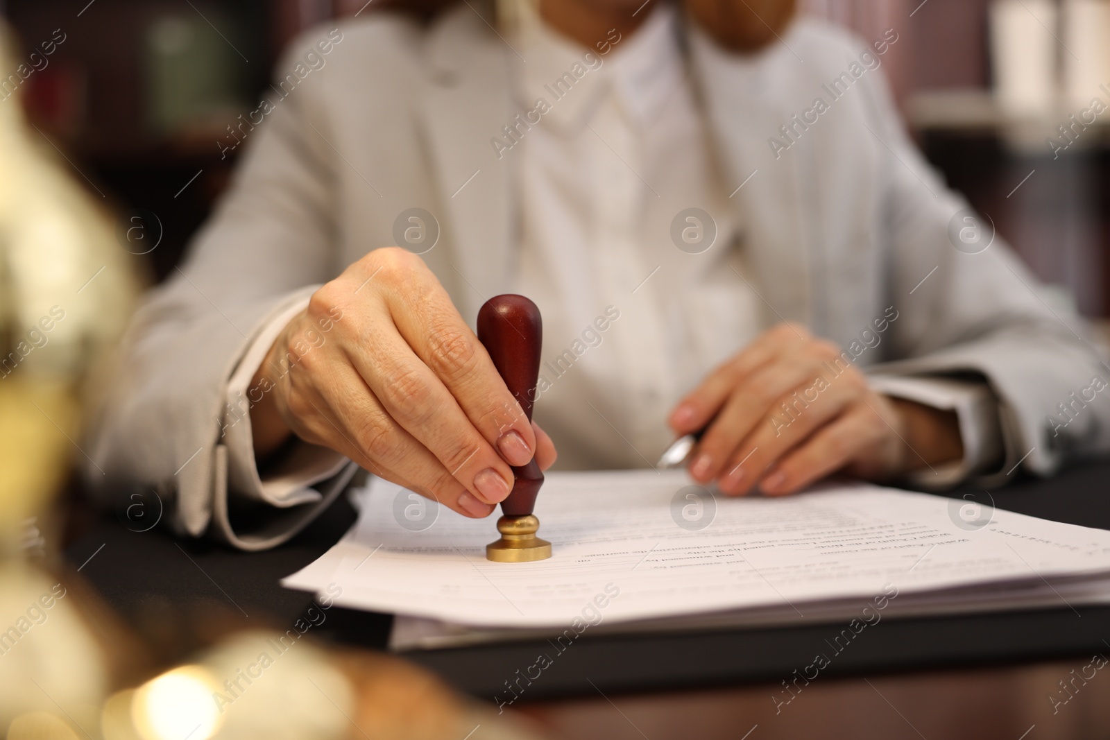 Photo of Notary stamping document at table in office, selective focus