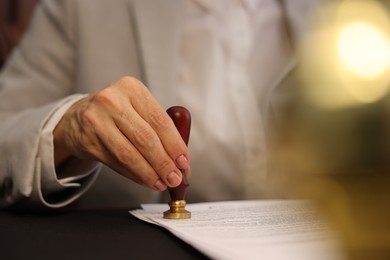 Photo of Notary stamping document at table in office, selective focus