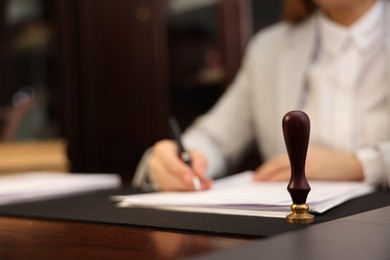 Photo of Notary working at table in office, focus on stamp