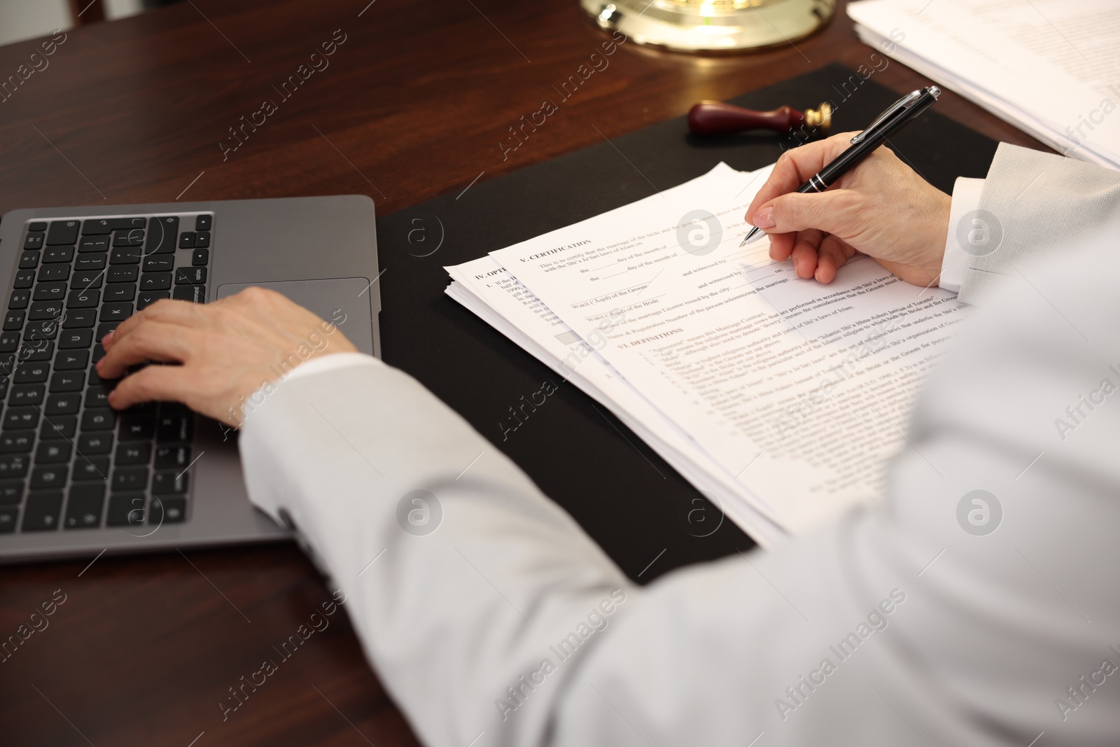 Photo of Notary working with laptop at wooden table, closeup