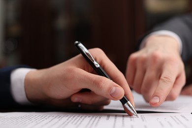 Photo of Notary showing client where to sign document in office, closeup