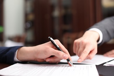 Photo of Notary showing client where to sign document in office, closeup