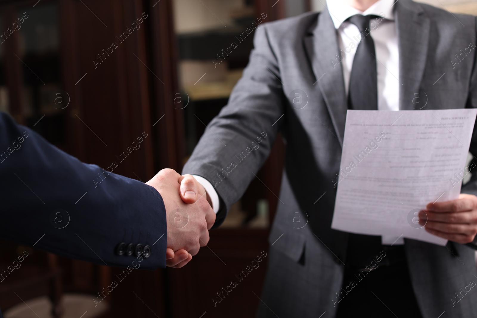 Photo of Notary shaking hands with client in office, closeup