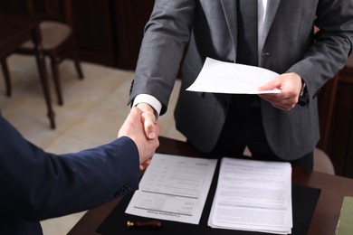 Photo of Notary shaking hands with client in office, closeup